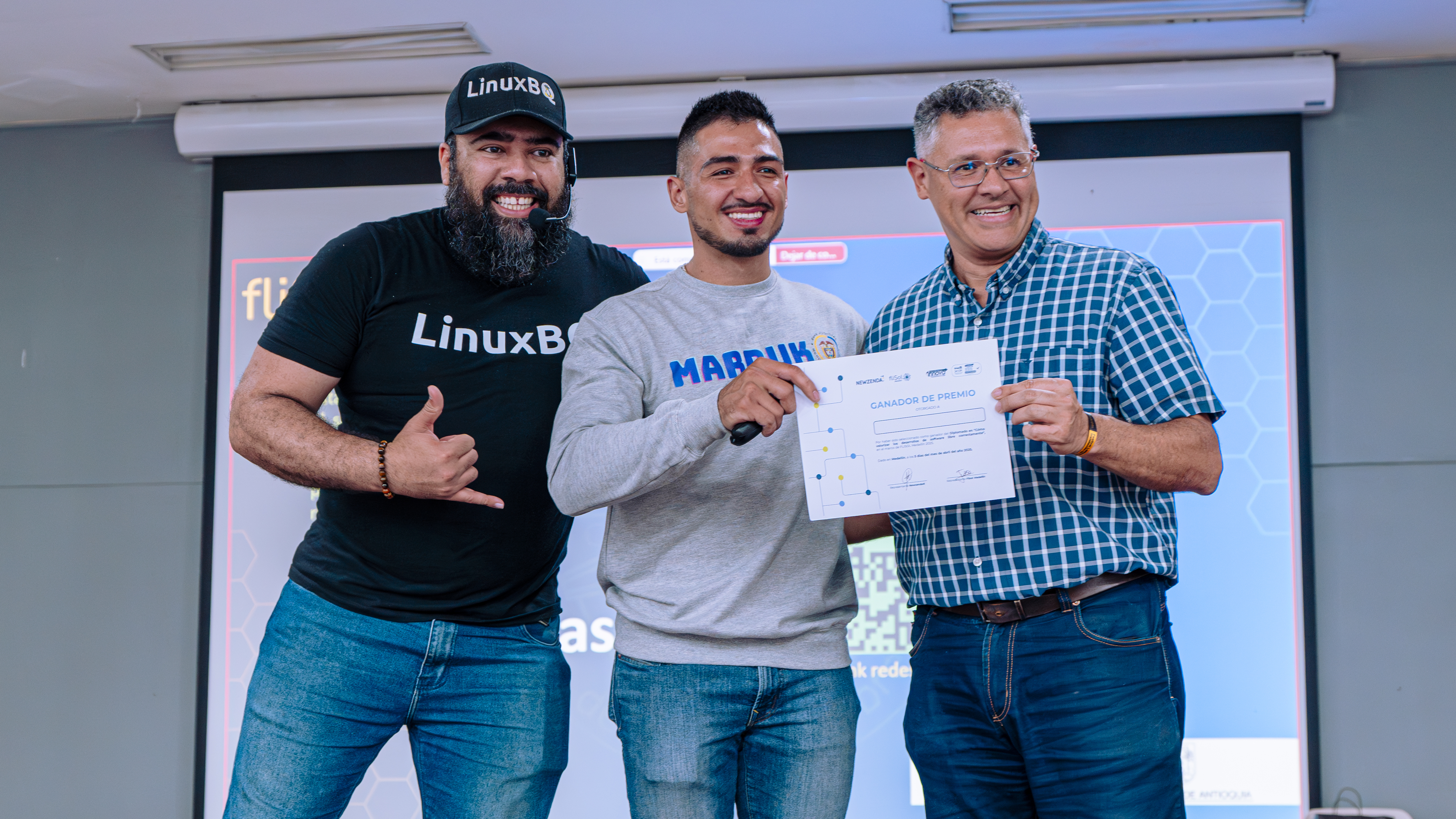 Daniel recibiendo certificado de manos del equipo organizador de FliSol, logo de FliSol en pantalla