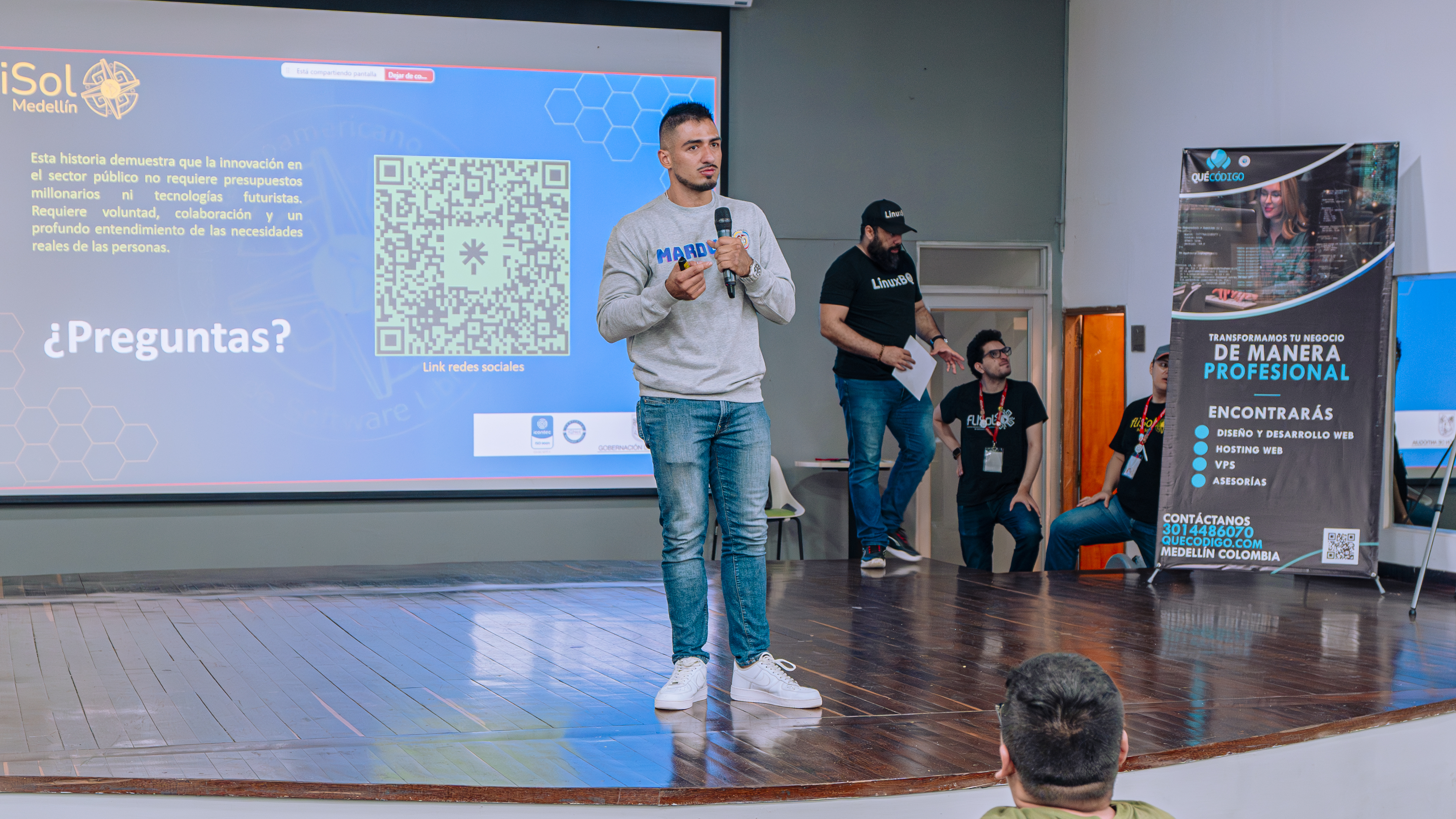 Daniel en el escenario durante la ronda de preguntas, con diapositiva “¿Preguntas?” visible